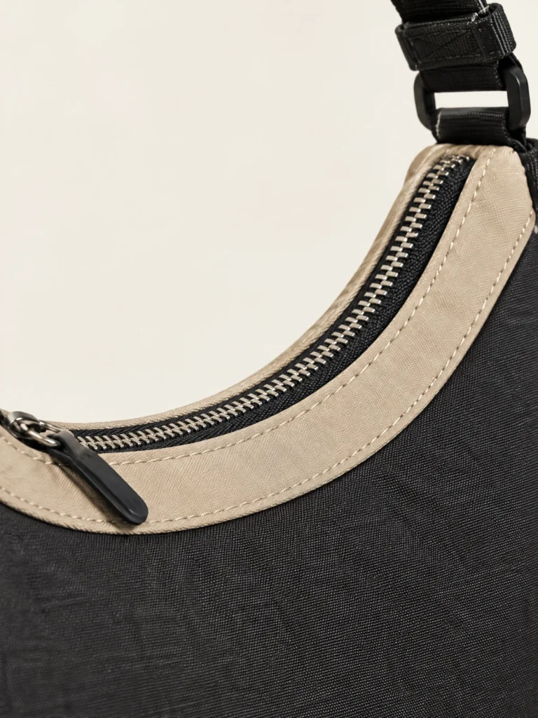 Close-up of Sand curved zip panel on Asphalt Arc Shoulder Bag