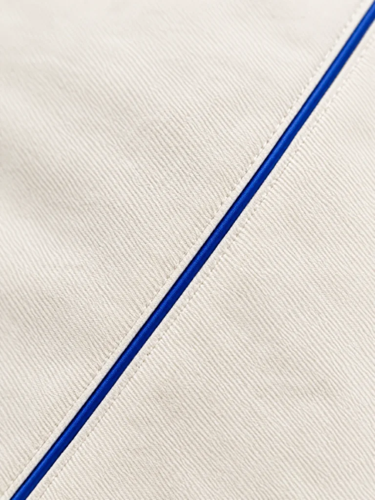 Close-up of diagonal seam with Lane Blue piping on Chalk fabric