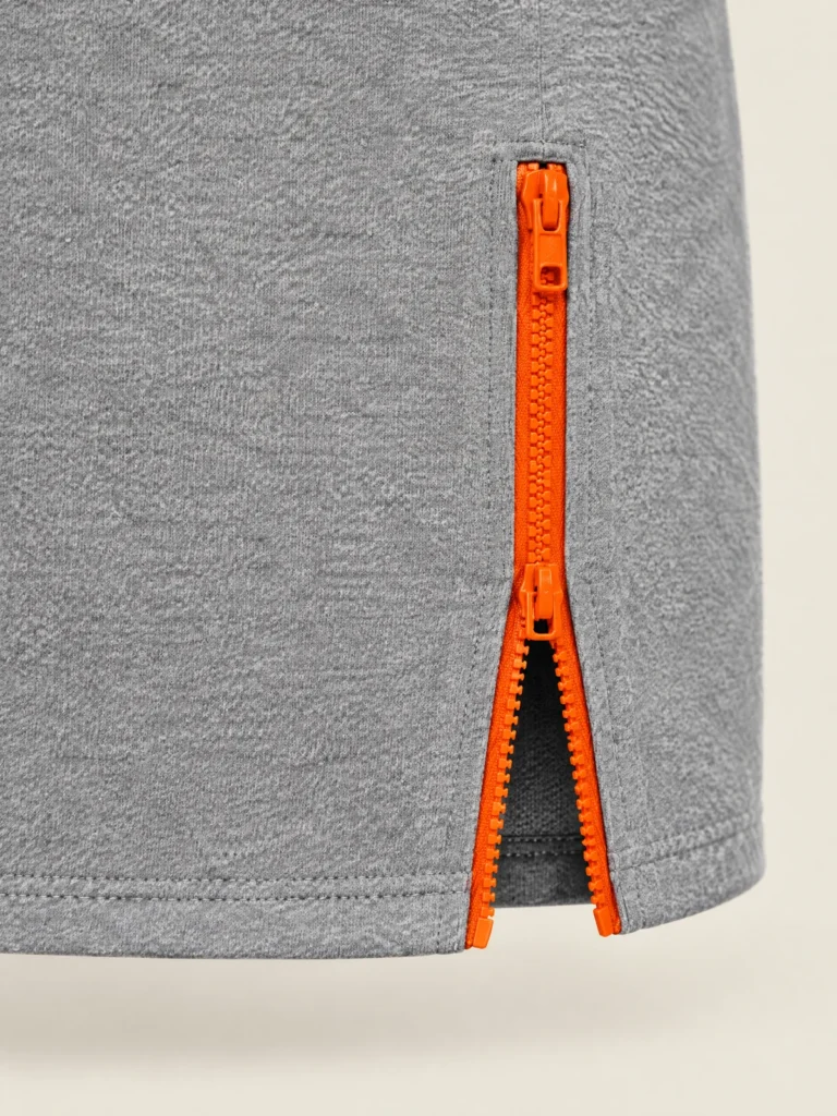 Close-up of Signal-orange vertical zip at front hem of Hemline Zip Mini