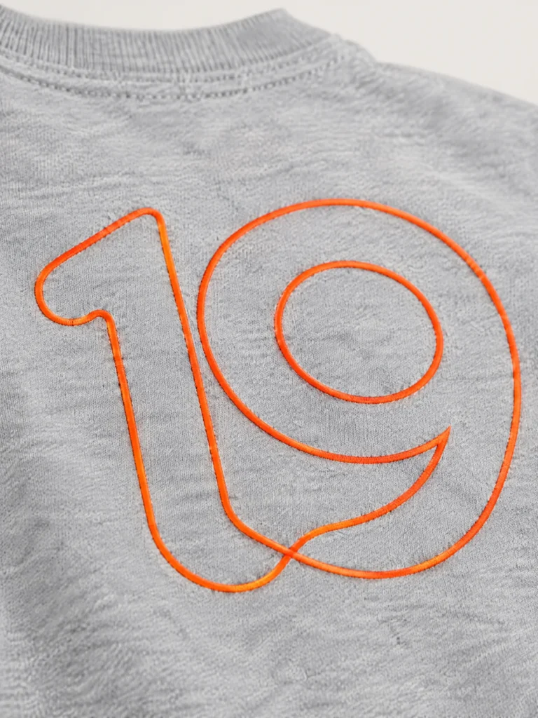 Close-up of Signal orange rib cuff and looped 19 outline graphic detail
