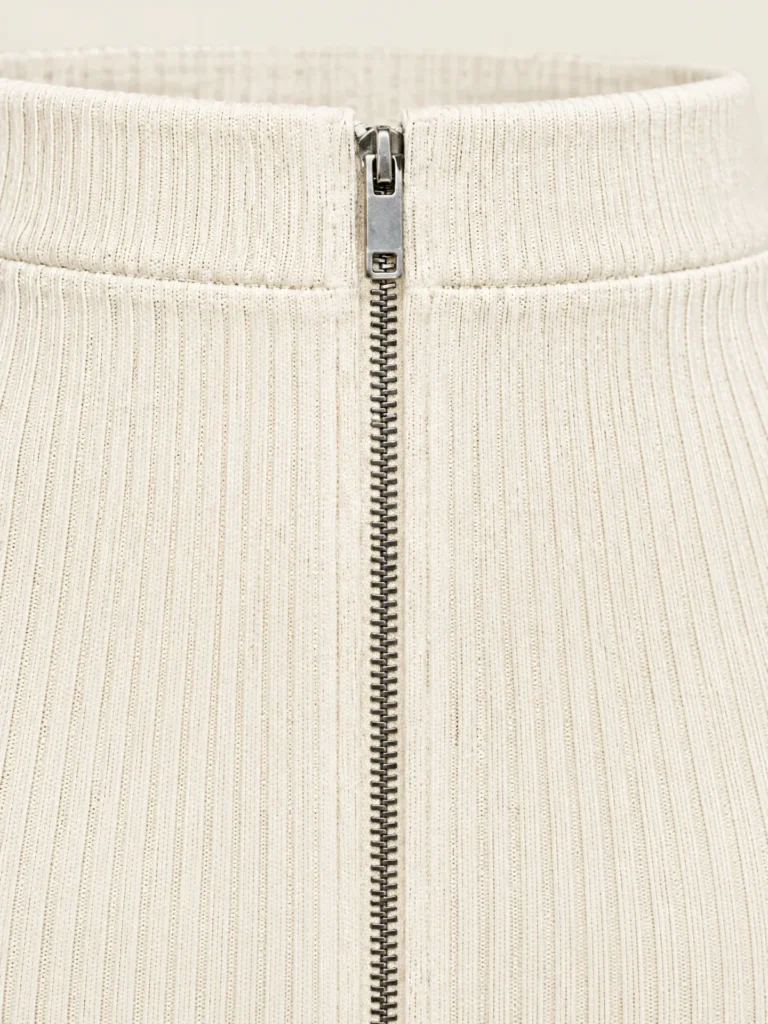 Close-up of centre-front metal zip and fine rib texture in Chalk